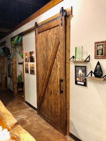 Picture of a hallway with a wooden barn-style door, and various awards and certificates hung on the wall.